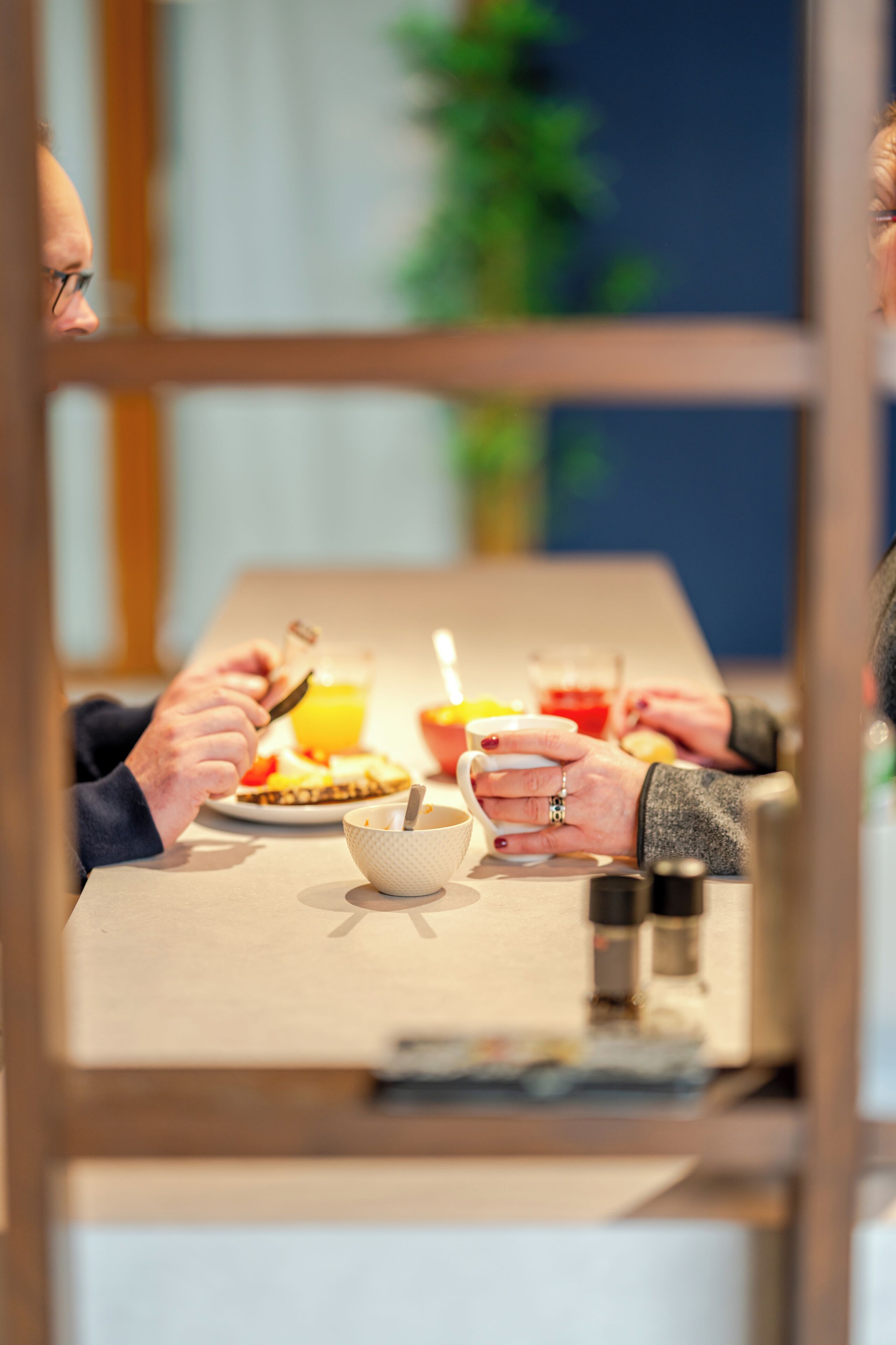 Una mesa de comedor con un plato de comida, un vaso de jugo de naranja y una taza.