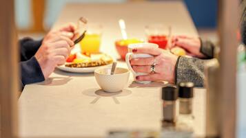 A dining table with a plate of food, a glass of orange juice, and a cup.