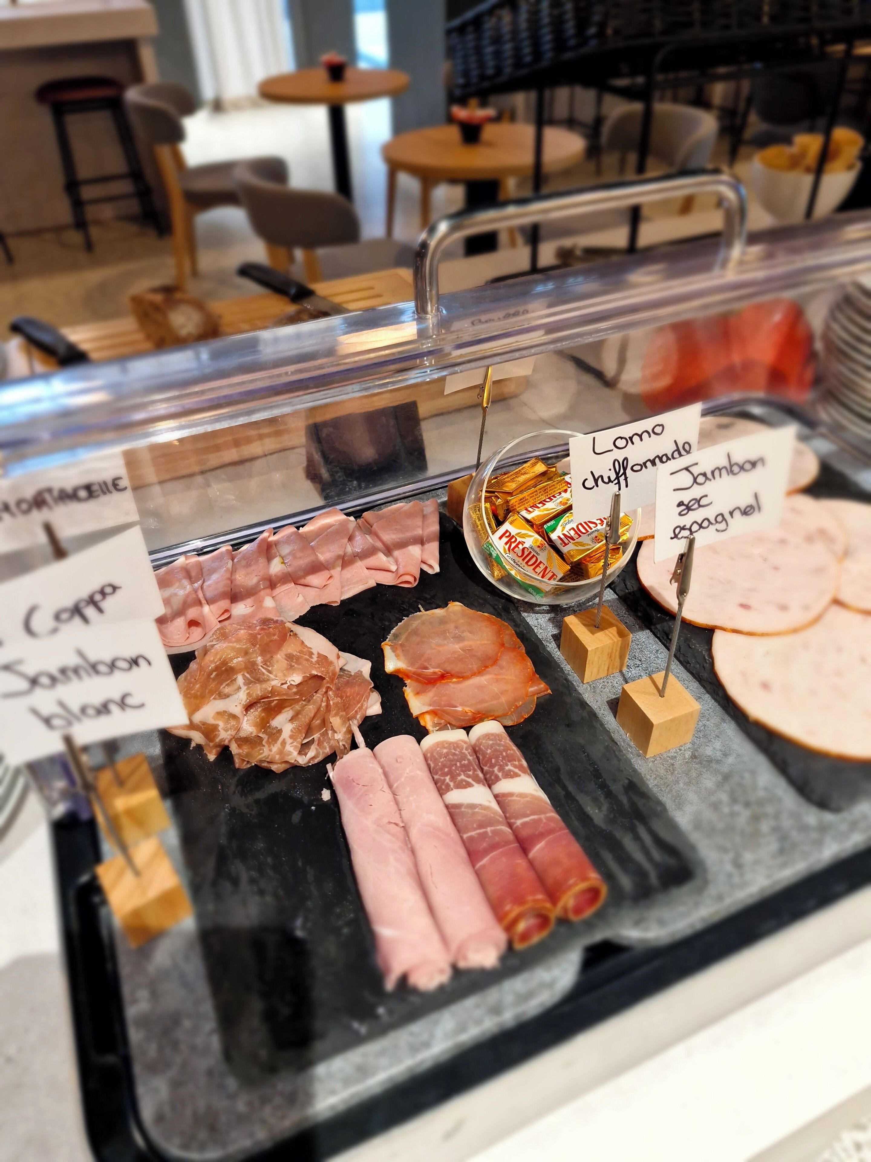A deli counter with various types of cured meats displayed, including labels for each type.