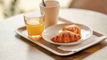 A breakfast tray with croissants and a glass of orange juice on a wooden table.