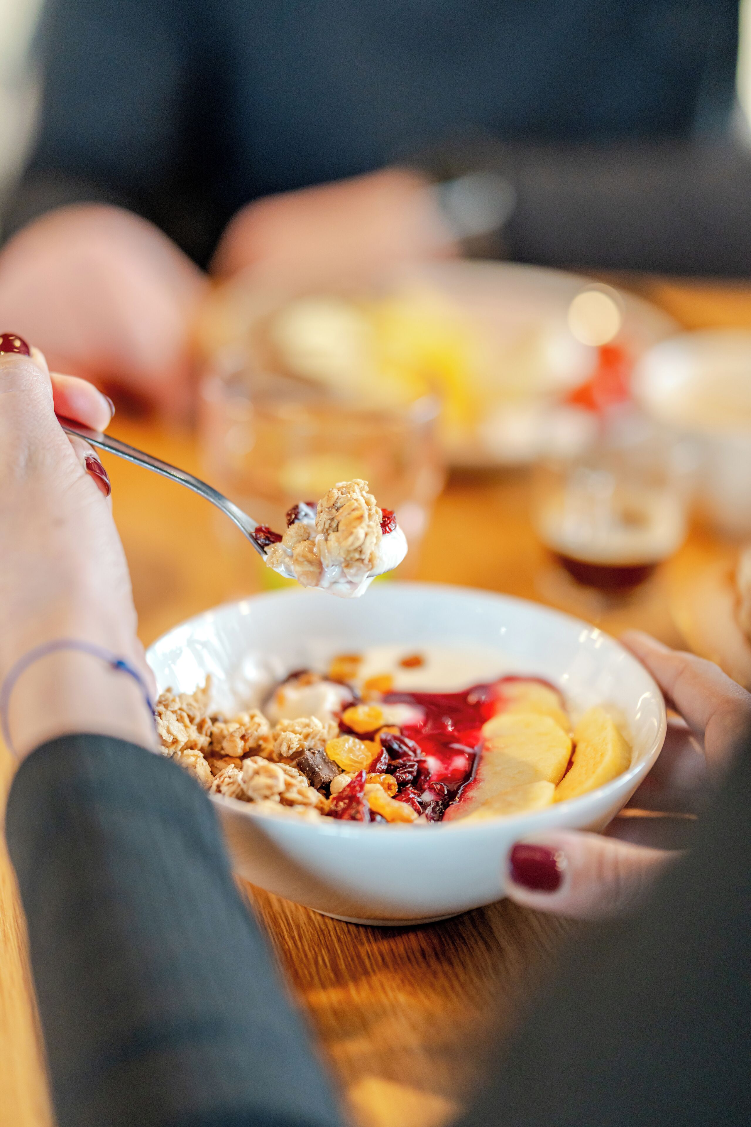 A close-up of a person eating cereal with fruits and yogurt.