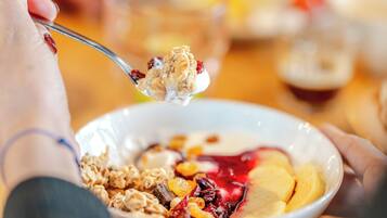 A close-up of a person eating cereal with fruits and yogurt.