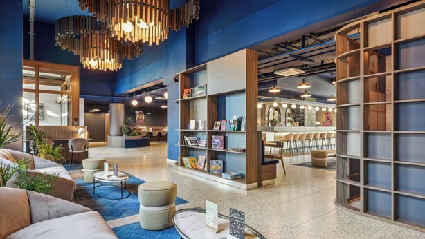 Un vestíbul modern amb zones d'estar, una recepció i una prestatgeria.