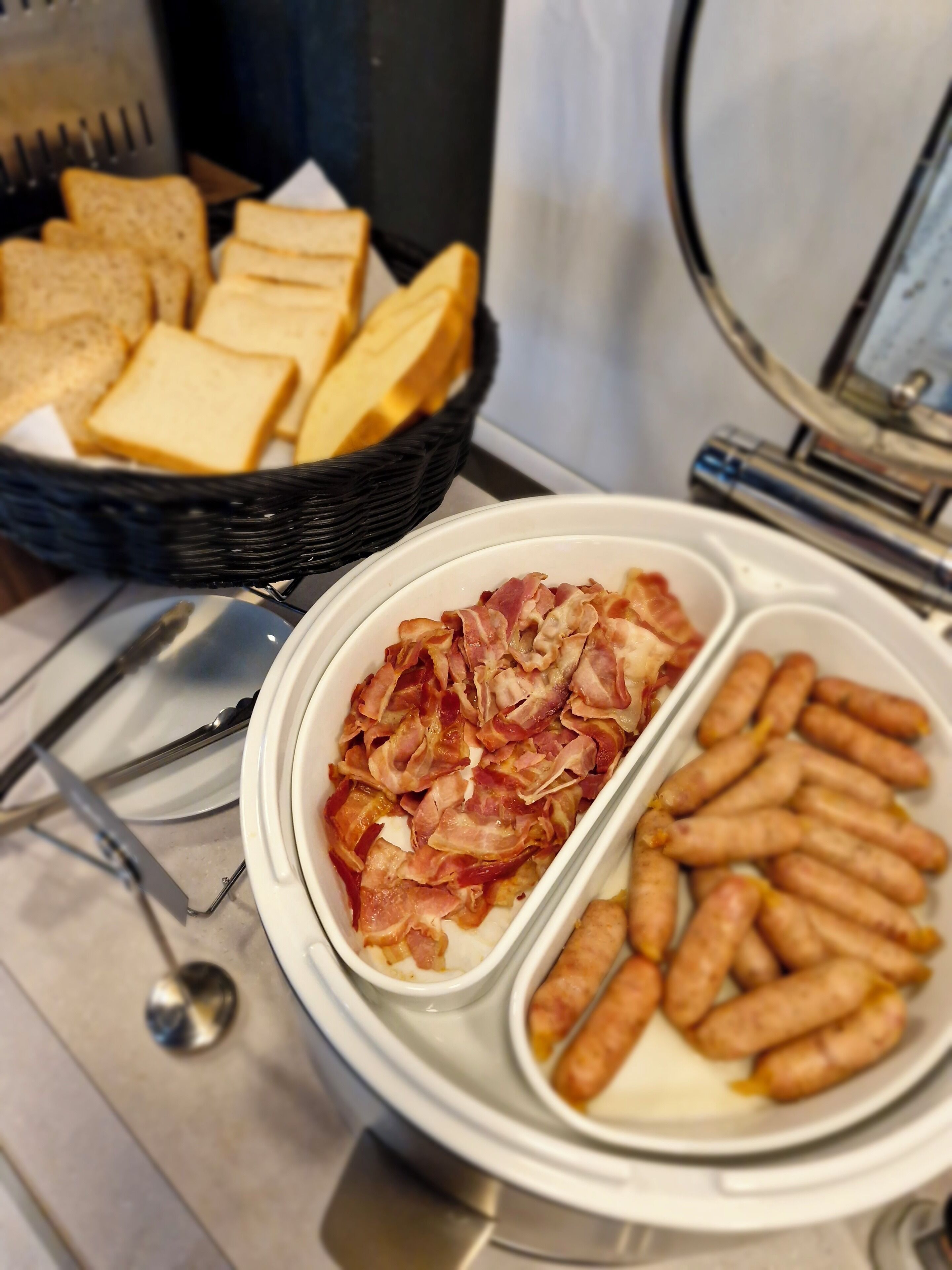Un bufé de desayuno con pan, tocino y salchichas.