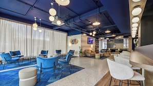 Zona d'estar àmplia amb seients blaus i blancs, una barra amb tamborets i una gran pantalla de televisió.