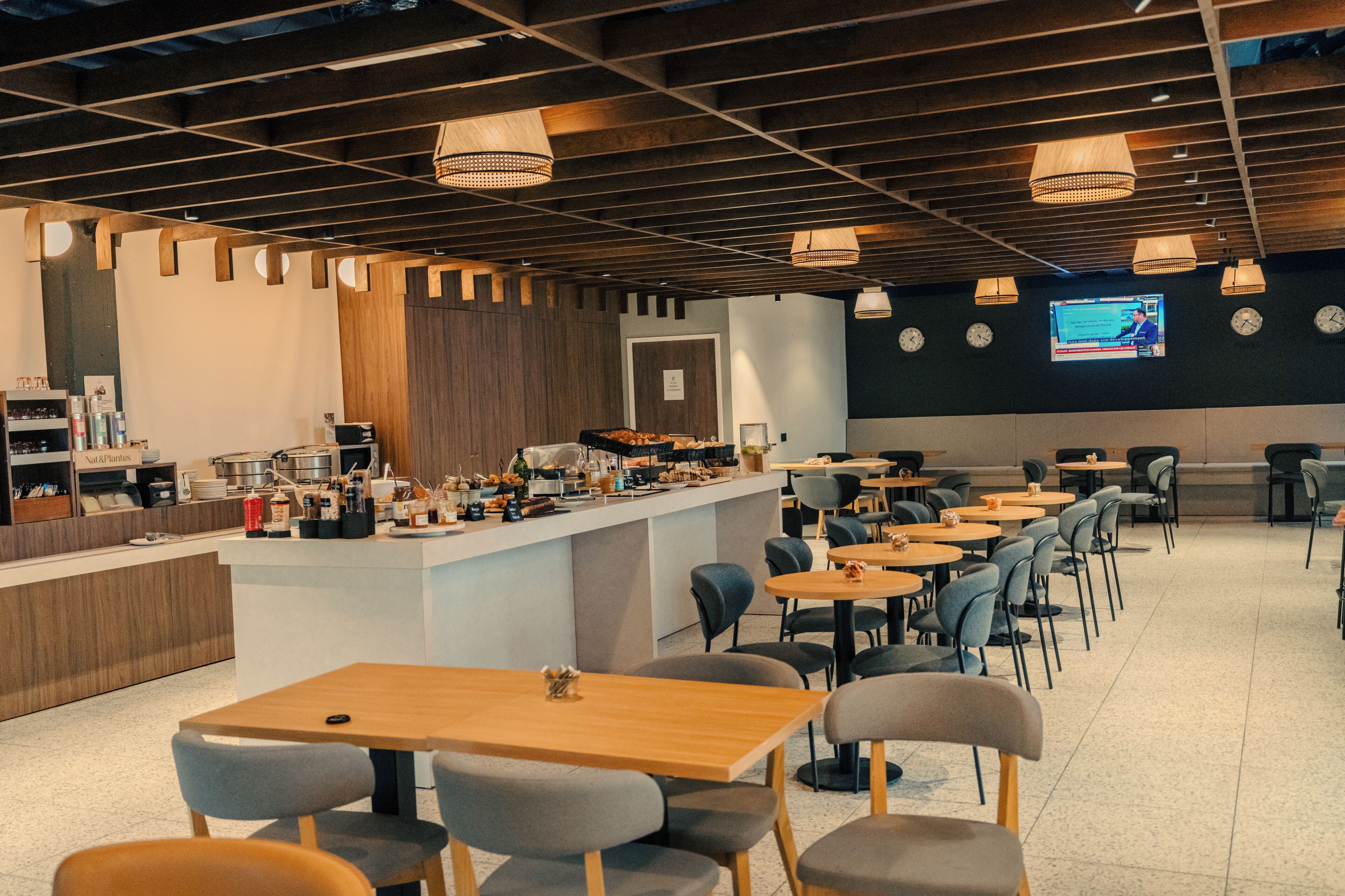 Un restaurant moderne doté d’un bar, de plusieurs espaces pour s’asseoir et d’un écran de télévision fixé au mur.