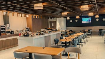 Un restaurant moderne doté d’un bar, de plusieurs espaces pour s’asseoir et d’un écran de télévision fixé au mur.