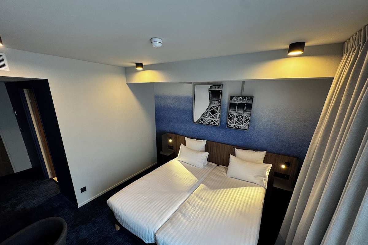 A hotel room with a bed, a chair, and a nightstand.