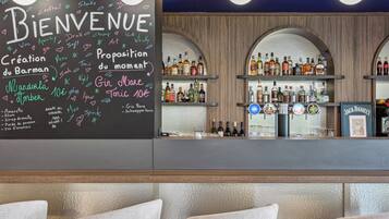 A bar area with a chalkboard menu listing drinks and prices, shelves of liquor bottles, and a framed picture of Jack Daniel's.
