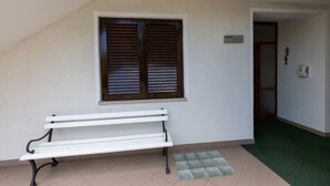 Un banc blanc dans un couloir, avec une fenêtre et une porte.
