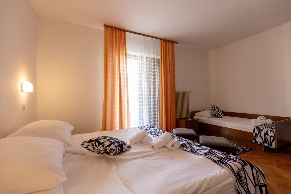 Una habitación de hotel con una cama grande, otra más pequeña, un escritorio y una silla.