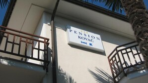 Un immeuble avec une enseigne indiquant « Pension Kovac » et des balcons dotés de garde-corps en métal.