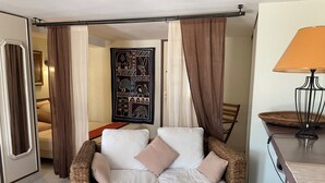 Un espace de vie comprenant un canapé en osier, une table basse en bois et une lampe.