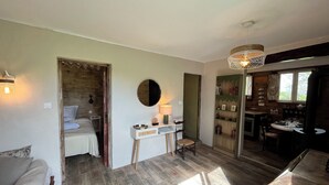 Een gezellige kamer met een bed, een tafeltje met een lamp, een stoel en een boekenkast.