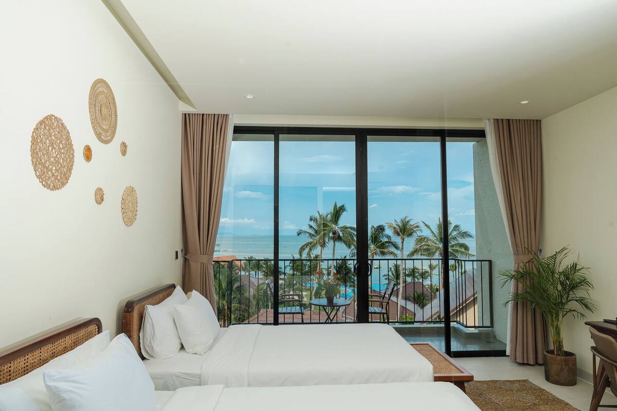 Ein Hotelzimmer mit großem Balkon, einem Bett, einem kleinen Tisch und einem Blumentopf.