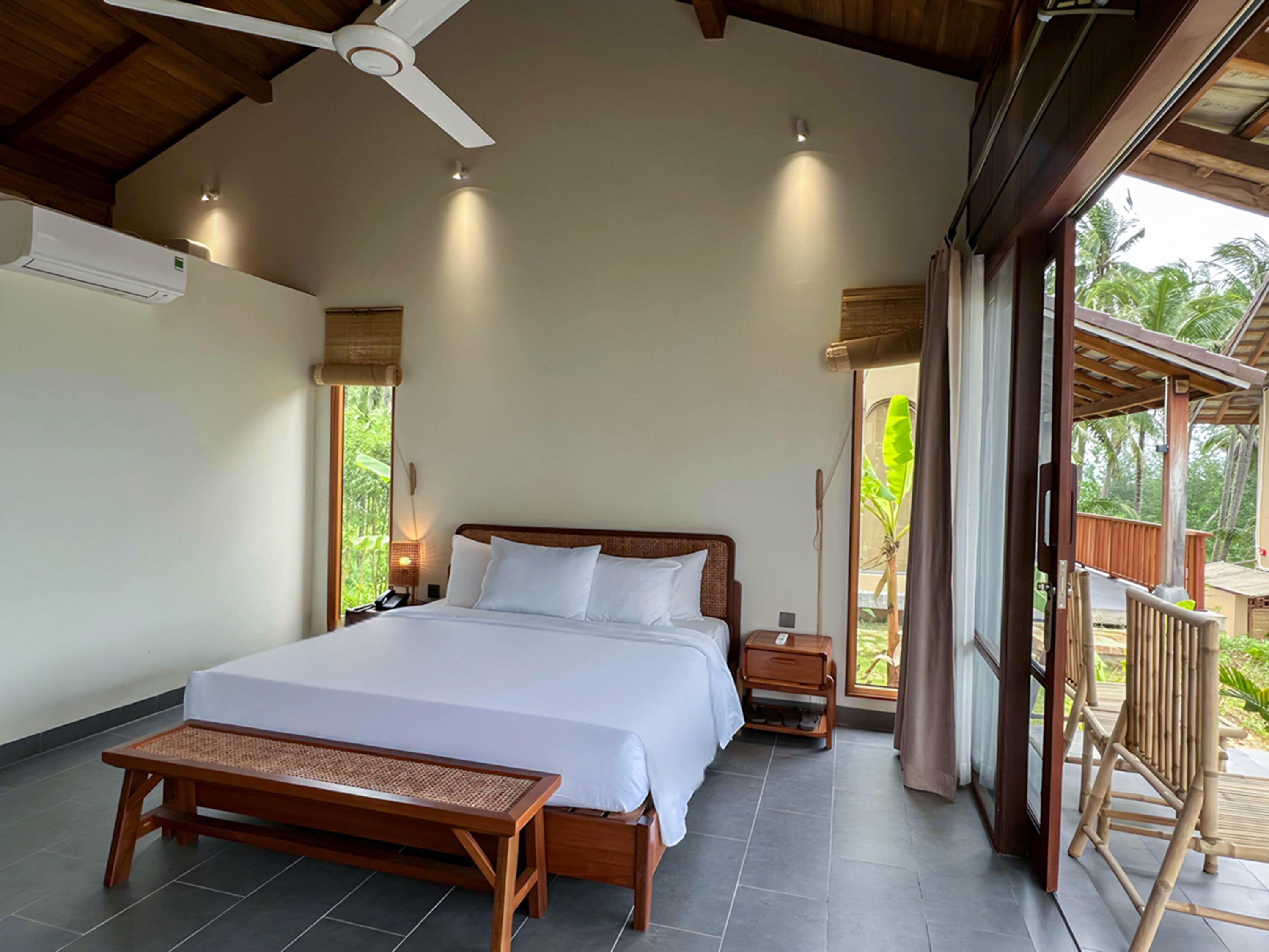 A spacious bedroom with a large bed, a wooden bench, and a ceiling fan.