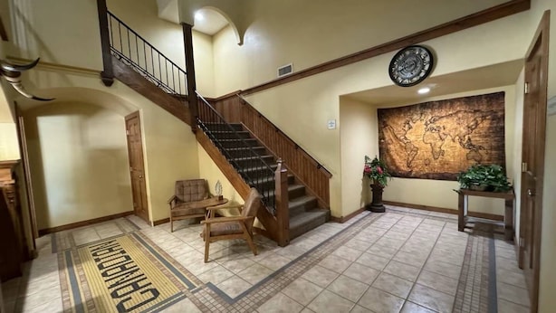 A spacious lobby with a wooden staircase, a world map mural, and a tactile floor for the visually impaired. - Oriental Hotel (Canadian)