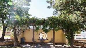 An outdoor patio area with a circular window, two tables, and chairs, surrounded by trees. - Oriental Hotel (Canadian)