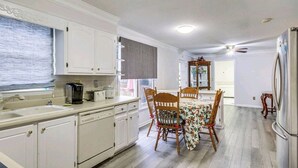 A kitchen with white cabinets, a dining table with chairs, a refrigerator, and a window with blinds. - Masters Retreat! quite, great location 4BDR House (Augusta)