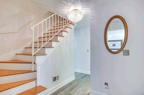 A staircase with wooden steps and white railings, a chandelier, and a mirror on the wall. - Masters Retreat! quite, great location 4BDR House (Augusta)