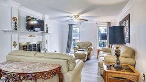 A spacious living room with a fireplace, a ceiling fan, and a large window. - Masters Retreat! quite, great location 4BDR House (Augusta)