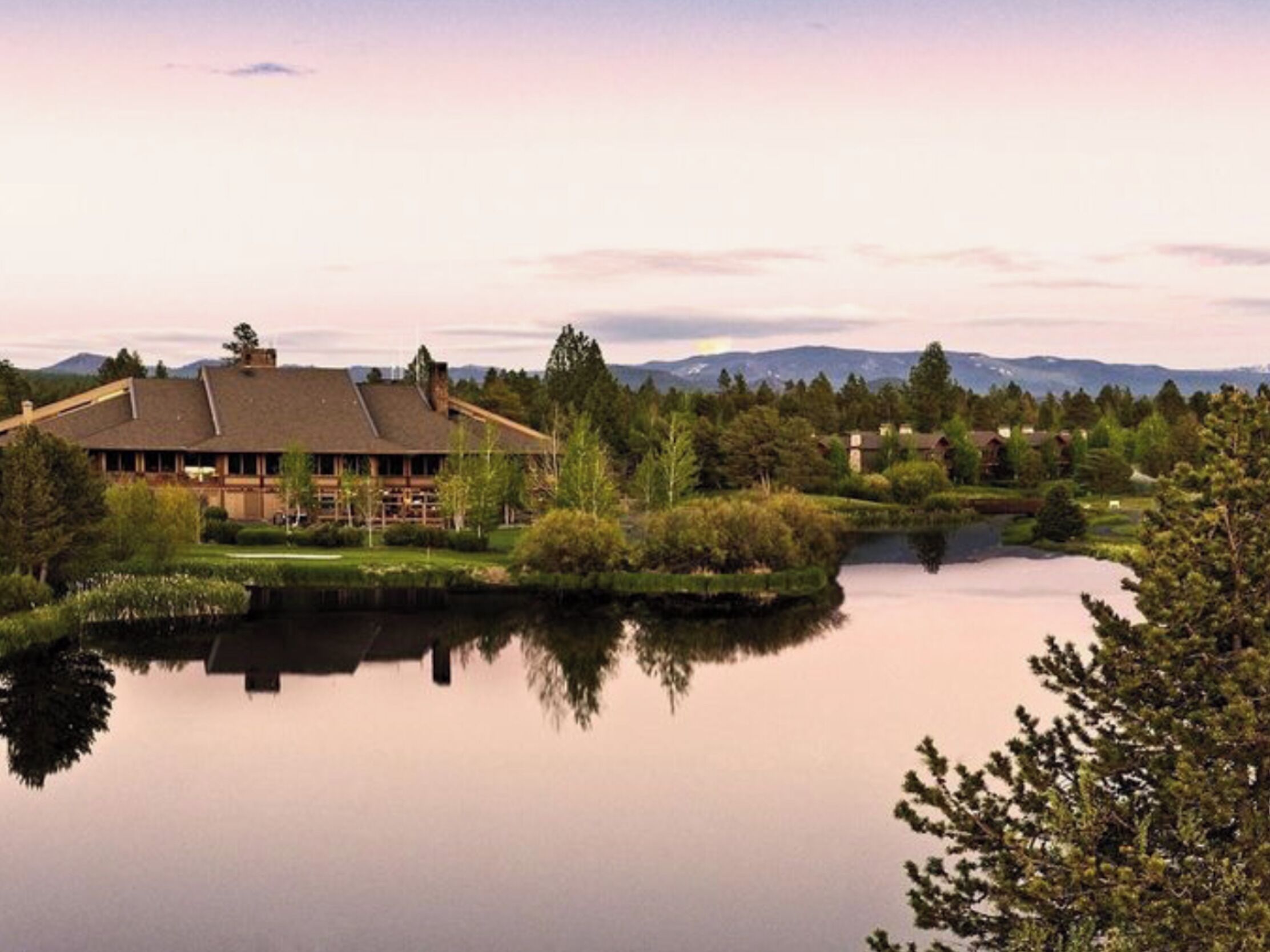 A lodge with a large building and a lake in the foreground.