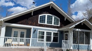 Une maison à deux étages avec un porche, une cheminée et une grande fenêtre.