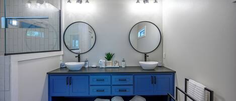 Une salle de bain avec deux lavabos, un miroir et une douche.