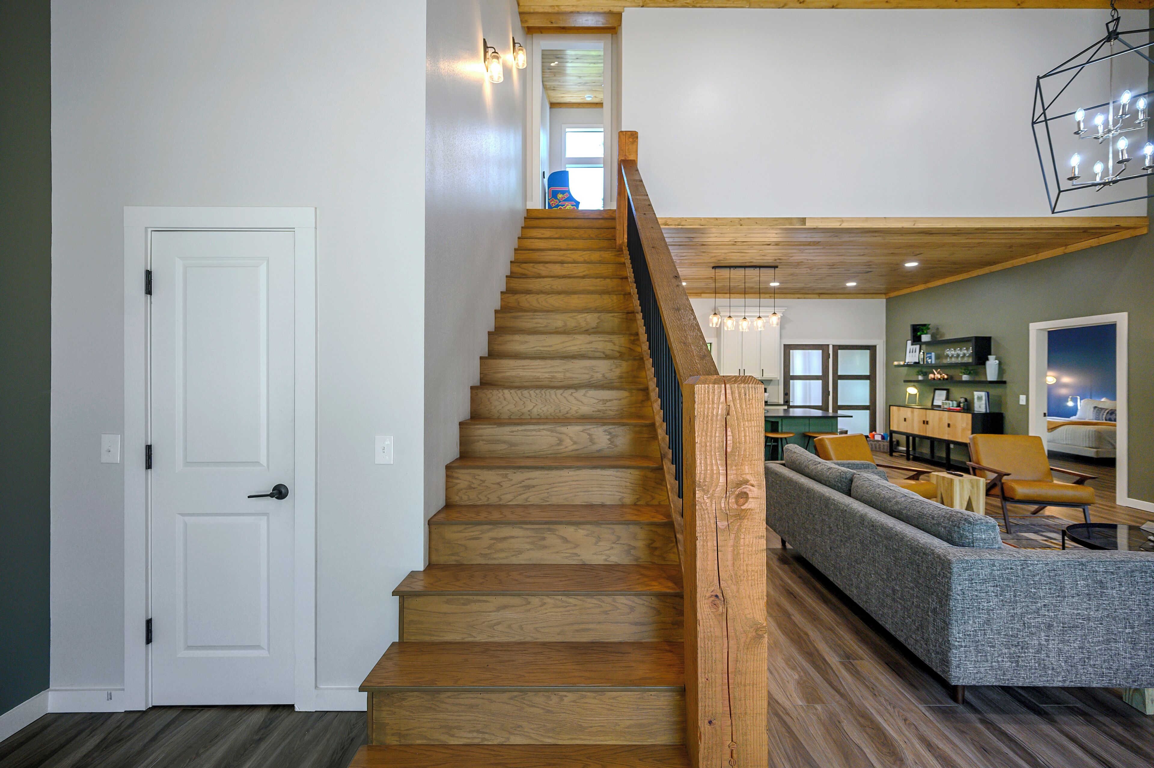 A wooden staircase with a handrail leading to a living area with a sofa and a dining table.