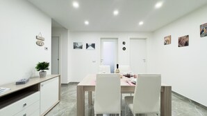A modern dining area with a wooden table, white chairs, and a small potted plant. - Casa Venturini by Ca-sa Check (Chioggia)