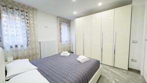 A bedroom with a bed, curtains, a radiator, and a wardrobe. - Casa Venturini by Ca-sa Check (Chioggia)