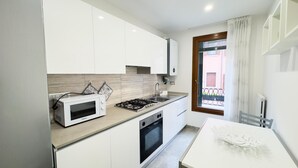 A modern kitchen with white cabinets, a built-in microwave, a gas stove, and a window with a view of the outside. - Casa Venturini by Ca-sa Check (Chioggia)