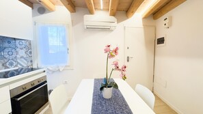 A modern kitchen with white cabinets, a stove, and a window with patterned tiles. - Maison la Digue by Ca-sa Check (Chioggia)