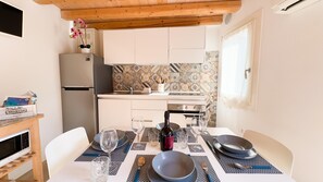 A compact kitchen with white cabinets, a refrigerator, and a tiled backsplash. - Maison la Digue by Ca-sa Check (Chioggia)