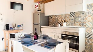 Una cucina moderna con zona pranzo per quattro persone. Dispone di frigorifero, forno e lavello con pannello posteriore in piastrelle.