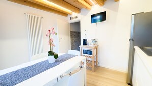 Una cucina moderna con frigorifero integrato, soffitto in legno e un piccolo tavolo con un vaso di fiori.