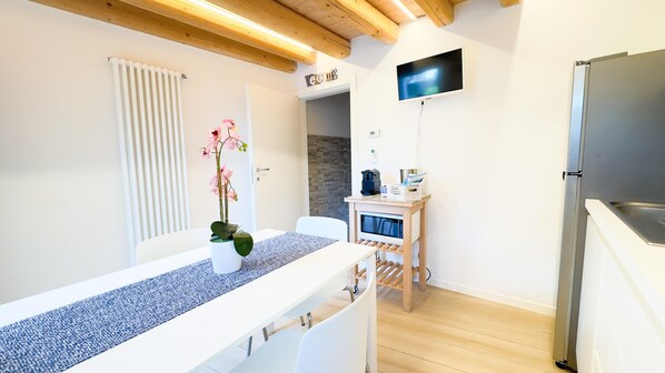A modern kitchen with a built-in refrigerator, a wooden ceiling, and a small table with a vase of flowers. - Maison la Digue by Ca-sa Check (Chioggia)