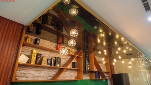 A hotel interior with a wooden and brick wall design, shelves with books and decorative items, and multiple hanging light fixtures.