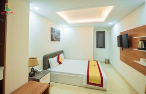 A hotel room with a bed, bedside table, lamp, and a TV mounted on the wall. - Bao Long Go Vap Hotel (Ho Chi Minh City)
