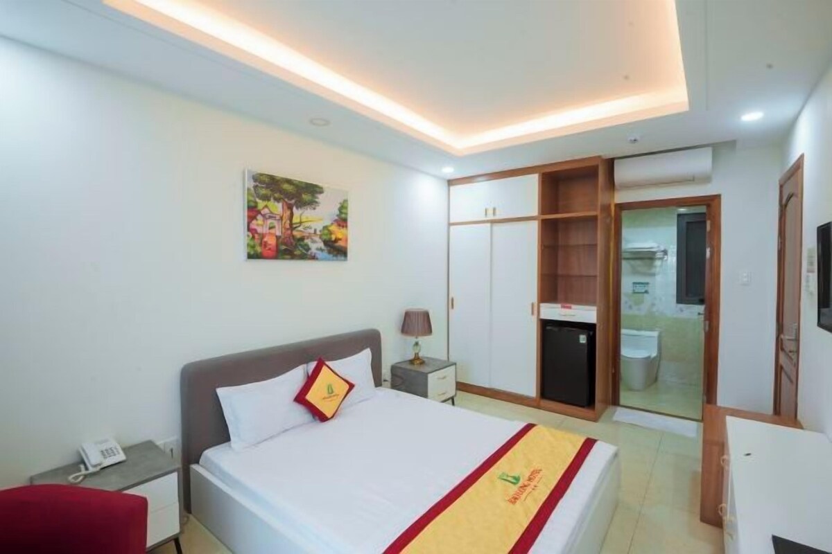 Une chambre d’hôtel avec un lit, une table de chevet, une lampe et un tableau au mur.