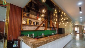 A hotel reception area with a marble counter, wooden shelving with various items, and pendant lighting. - Bao Long Go Vap Hotel (Ho Chi Minh City)