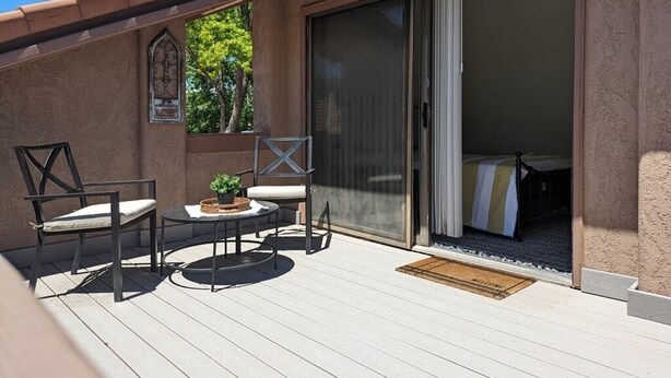 A patio with a table and chairs, a sliding glass door leading to a bedroom, and a small window with a decorative element.