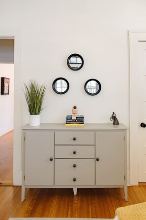 A neutral-toned room with a white door, a grey cabinet with three drawers, and three round mirrors on the wall.