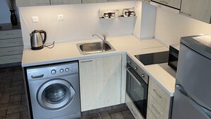 A compact kitchen with a washing machine, oven, and a built-in microwave.