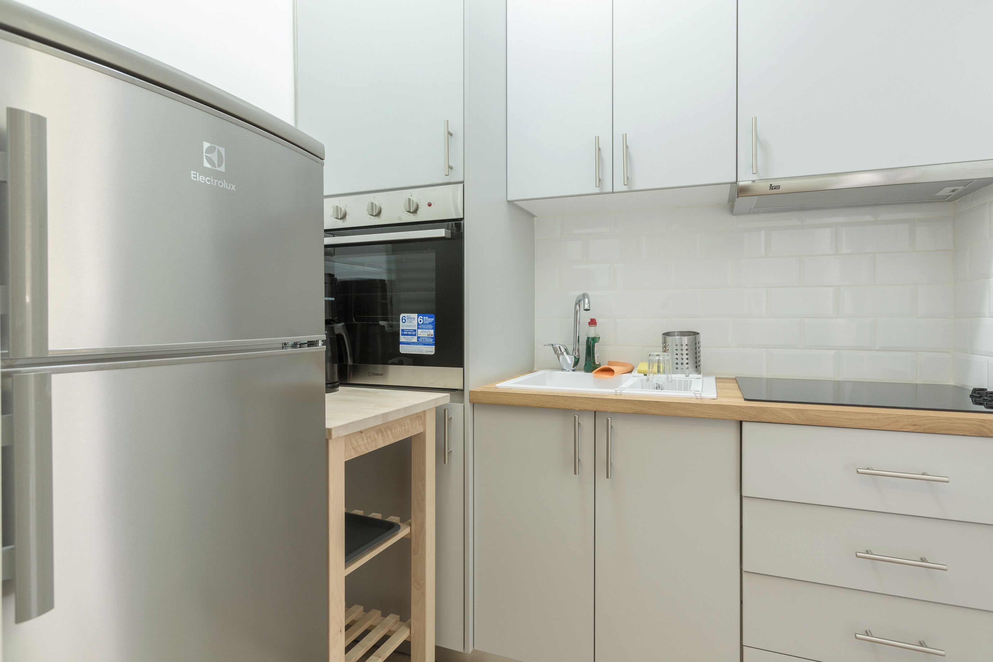Een moderne keuken met witte kastjes, een roestvrijstalen koelkast en een inbouwoven.