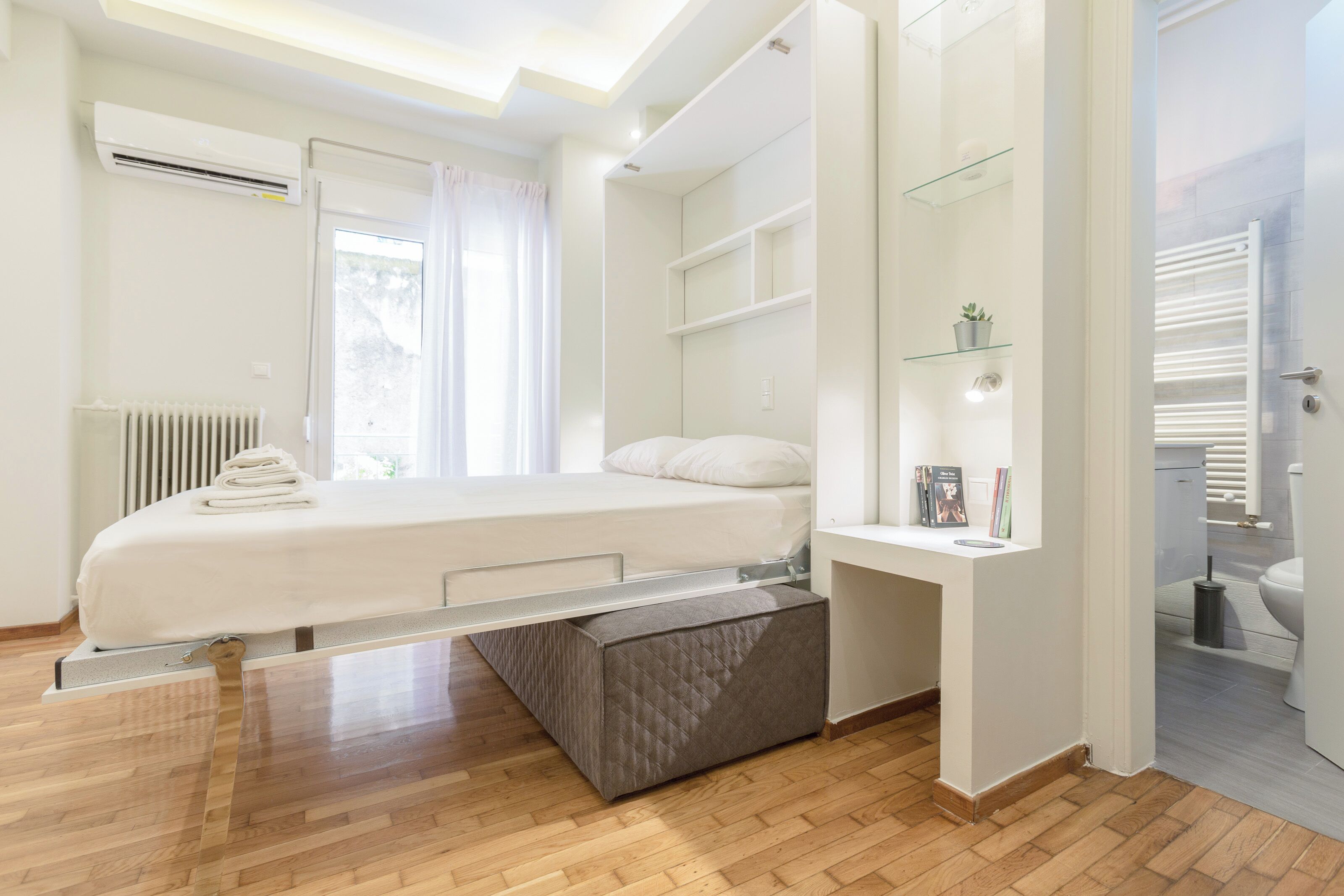 A modern bedroom with a bed, built-in shelves, a bedside table, and a radiator.