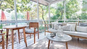 Une terrasse ensoleillée avec une table en bois, des chaises et un canapé.