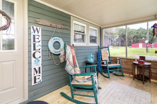 A porch with rocking chairs, a welcome sign, and a beach-themed decoration. - Set Sail to the Rusty Anchor! Your Perfect Getaway on Deal Island, MD (Deal Island Historic District)