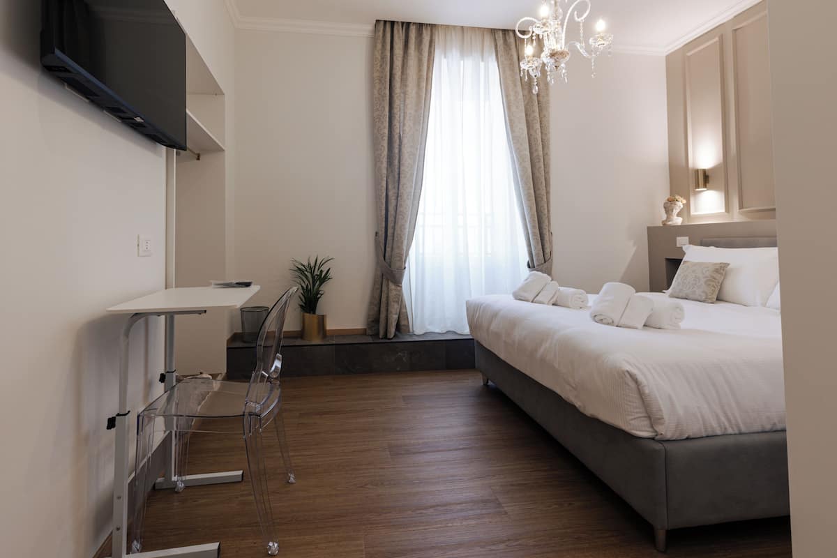 A modern bedroom with a bed, bedside table, and a TV mounted on the wall.