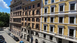 A multi-story building with a row of parked cars and motorcycles on the street below. - De Vince Luxury Suites - Roma Termini (Rome)